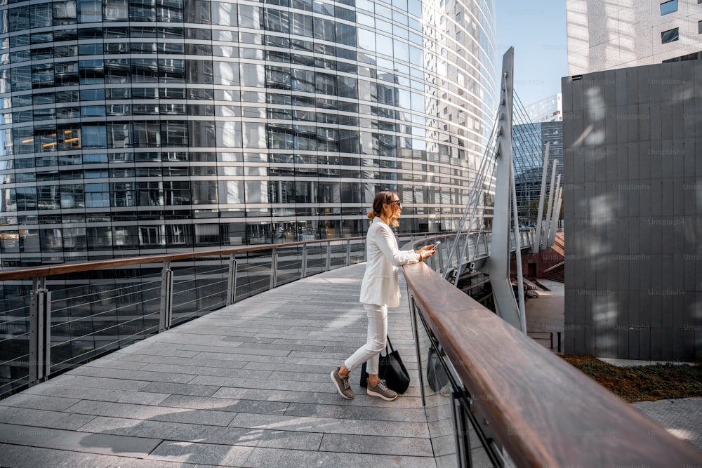 Donna d'affari che cammina all'aperto nel quartiere finanziario con edifici moderni sullo sfondo a Parigi