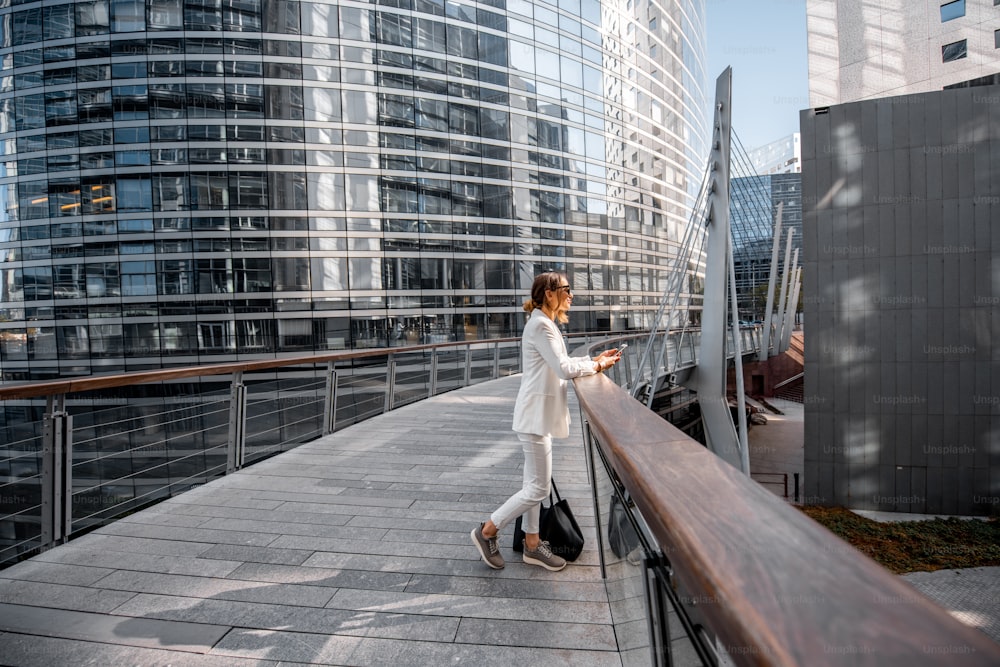 Business woman walking outdoors at the financial district with modern buildings on the background in Paris