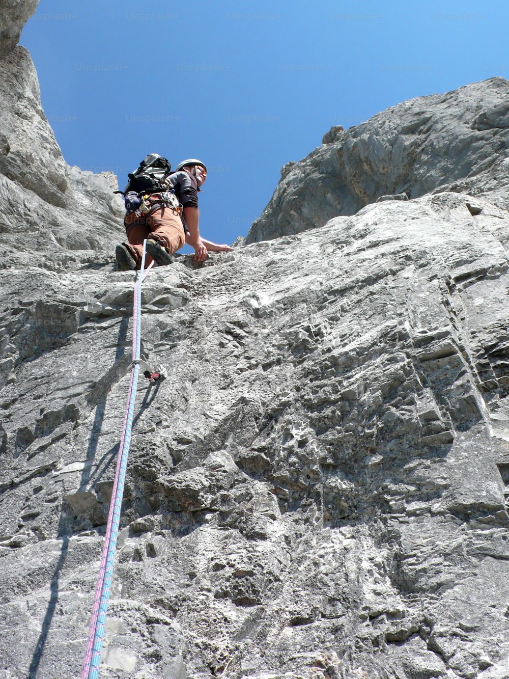 mountain guide rock climbing in the Alps of Switzerland in the Raetikon region near Klosters on a beautiful summer day