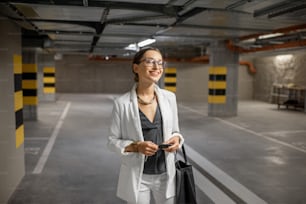 Young business woman walking with car keys in the underground parking of the new residential building