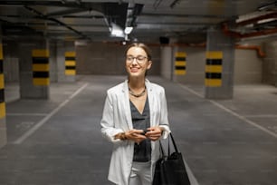 Young business woman walking with car keys in the underground parking of the new residential building