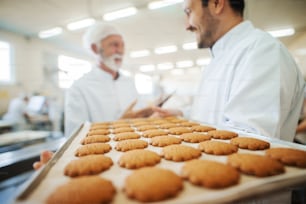 Close-up of two men talking and carrying plate with cookies.