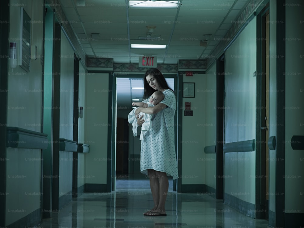 a woman standing in a hallway holding a baby