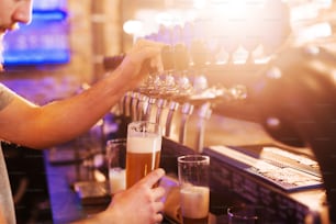 Close up of bartender pouring beer into glass. Pub interior.