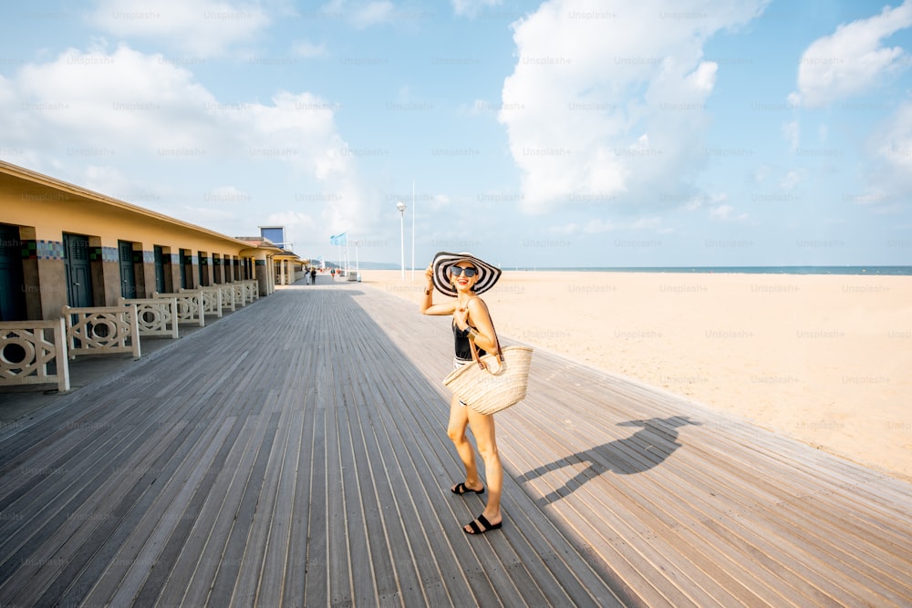 ノルマンディーの有名なフランスのリゾート地、ドーヴィルのロッカールームのあるビーチを歩く女性。広角ビュー