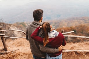 Happy Caucasian couple enjoying the view while hugging and standing at view point. Autumn season.