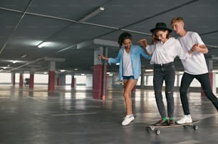 Skateboarding. Young People Having Fun At Parking. Friends Teaching Girl Riding On Skateboard. High Resolution