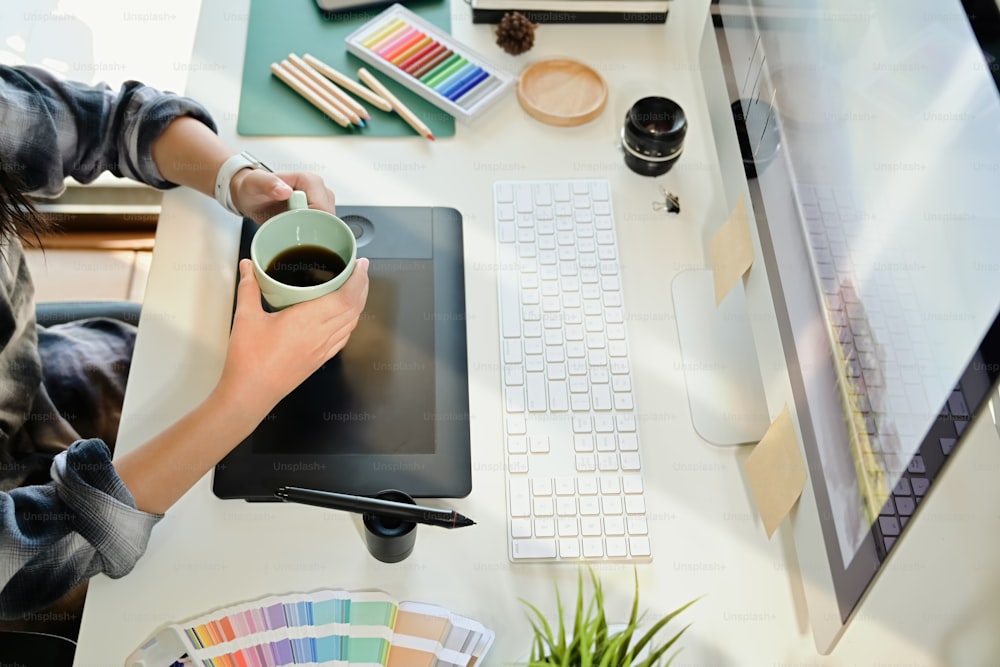 Diseñador creativo sosteniendo una taza de café en el lugar de trabajo del estudio de escritorio