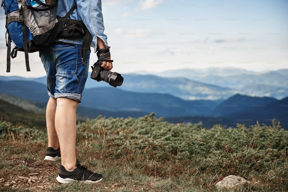 Modern camera. Professional experienced photographer holding his modern camera while traveling in the mountains