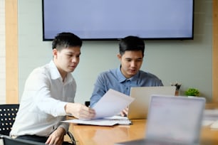 Dois colegas empresário que trabalha com computador e finanças documento em papel.