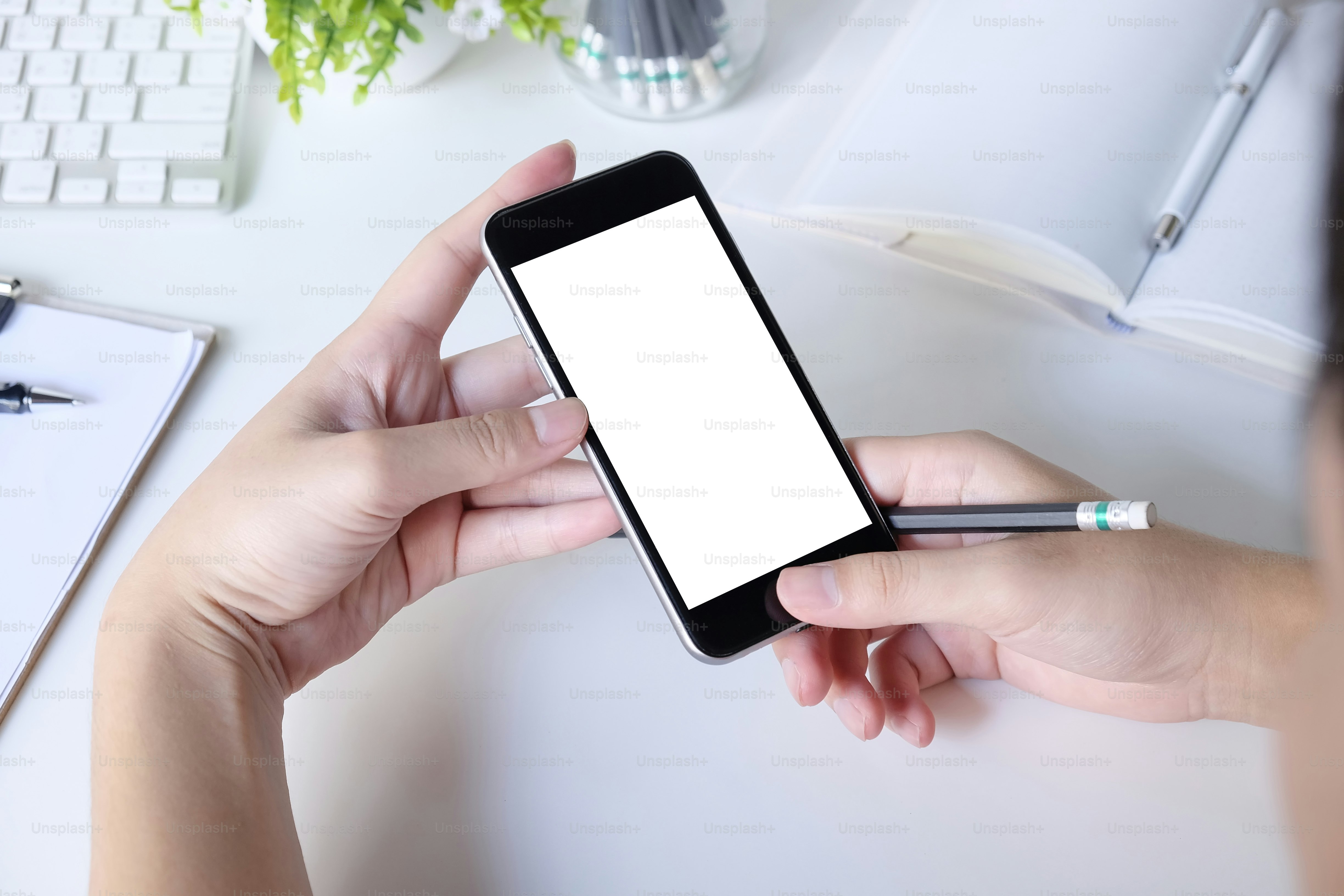 Mockup smartphone on hands working on office table with clipping path on display.