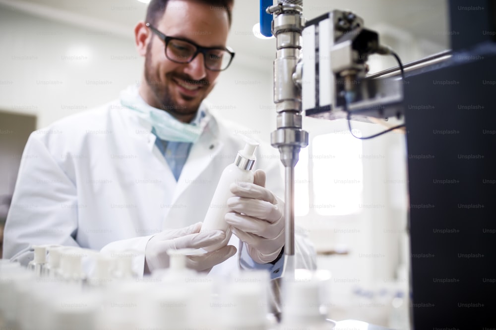 기술자가 화장품 실험실에 서 있는 동안 액체 비누로 병을 채우고 있다.