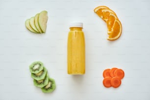 Cibo a bassa calloria. Frullato di arancia fresca con frutti isolati su sfondo bianco. Arancia, mele, carota e kiwi