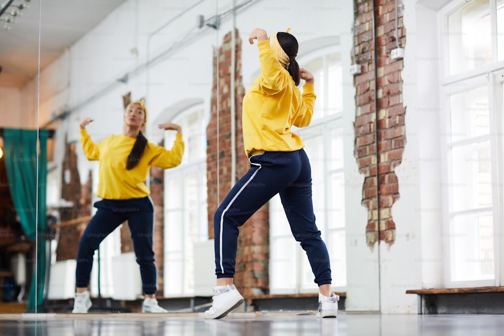 Jovem dançarino em treinamento de activewear na frente do espelho grande no estúdio de dança moderna