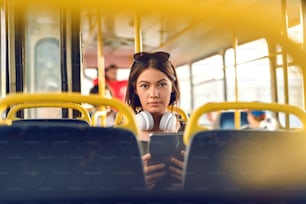 Young girl sitting in bus and holding tablet.