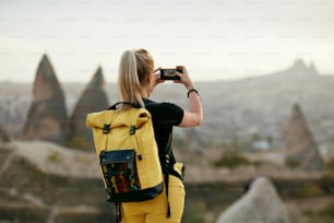 Frau reist, macht Fotos am Telefon der Naturlandschaft. Weiblich mit Rucksack macht Foto. Hohe Auflösung