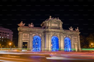 Nachtansicht der Puerta de Alcalá in Madrid, die weihnachtlich geschmückt ist.