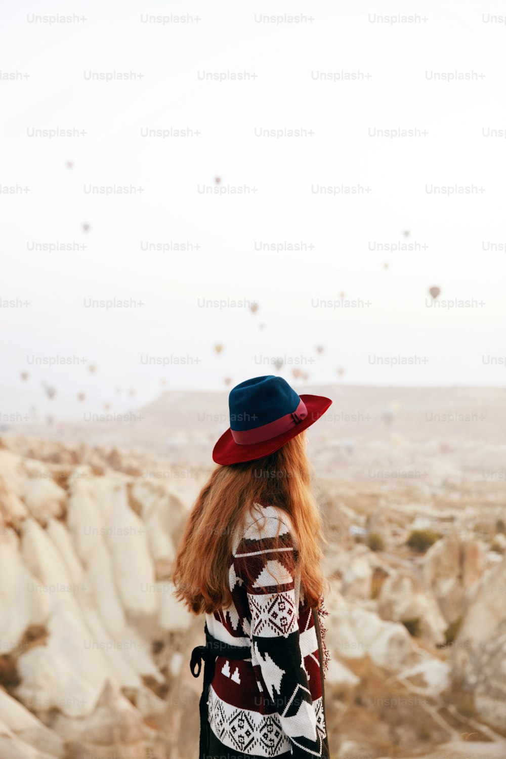 Viaggio. Bella donna in cappello che guarda le mongolfiere volanti dalla collina. Donna in abiti etnici in Cappadocia. Alta risoluzione