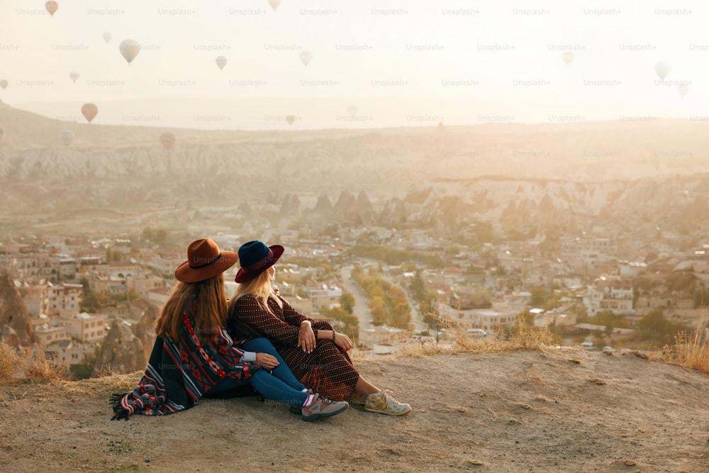 Le persone viaggiano. Donne in cappelli che si siedono sulla collina che si godono il volo di mongolfiere vista in Cappadocia Turchia. Alta risoluzione