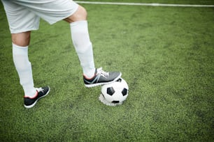 Giovane giocatore di calcio in piedi sul campo da calcio verde con il piede destro sulla palla