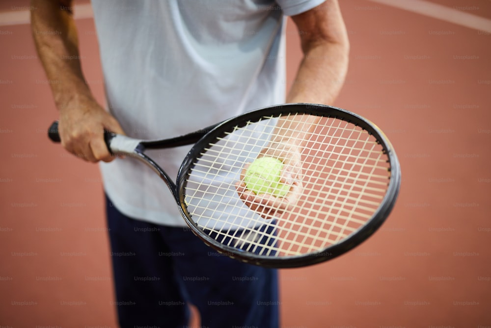 Contemporary tennis player holding racket and ball while standing on stadium