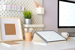 Scenario della scrivania dell'ufficio domestico con tablet a schermo vuoto mockup e computer desktop. Area di lavoro minima