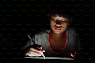 Teenage Asian girl using tablet drawing while lying on bed
