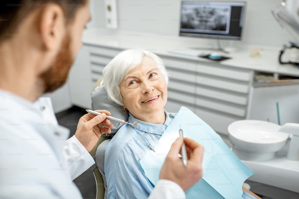 Ältere Frau während der ärztlichen Untersuchung mit männlichem Zahnarzt in der Zahnarztpraxis