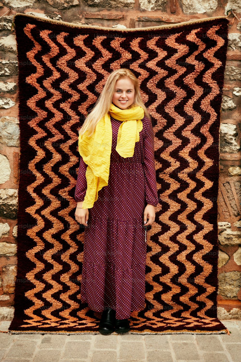 Hermosa mujer sonriente en vestido y bufanda con alfombra turca en el fondo. Alta resolución