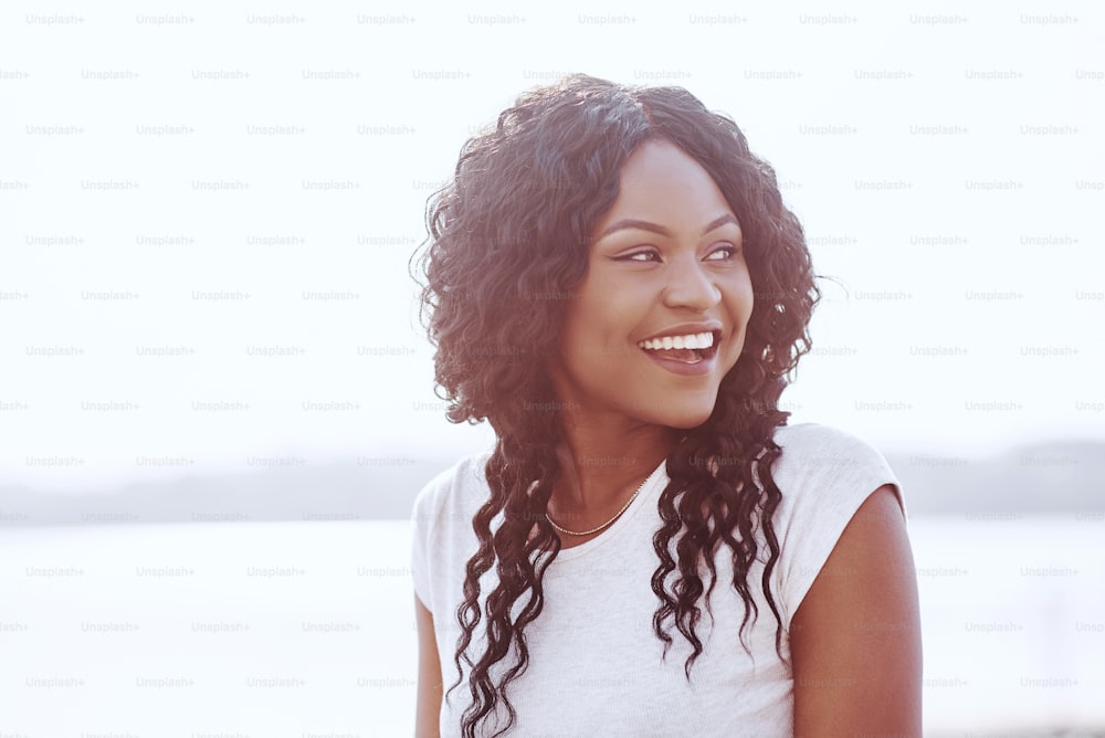 Portrait d’une jeune femme noire souriante avec une lueur de soleil.