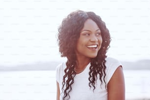 Retrato de una joven negra sonriente con el destello de la luz del sol.