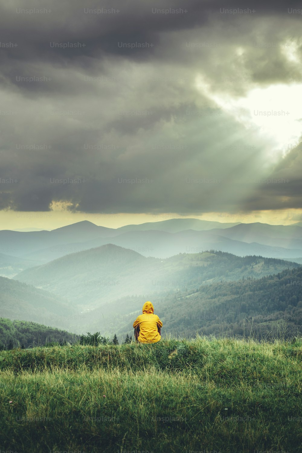 Rückansicht eines Tavelers, der an Hängen sitzt und sich von einer schönen Landschaft erfreut fühlt