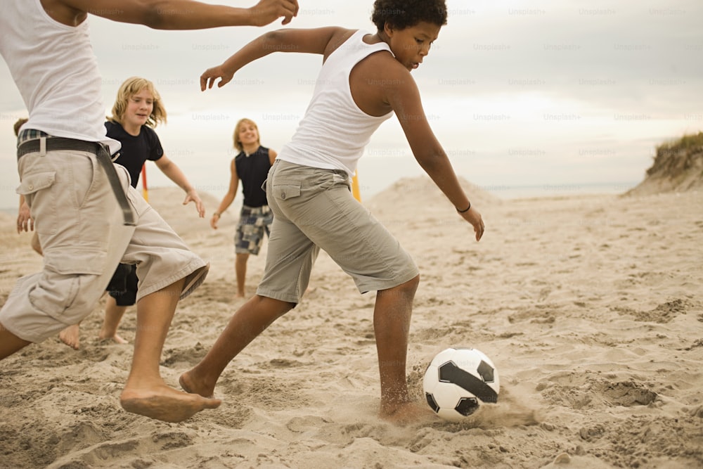 a group of people playing soccer on the beach