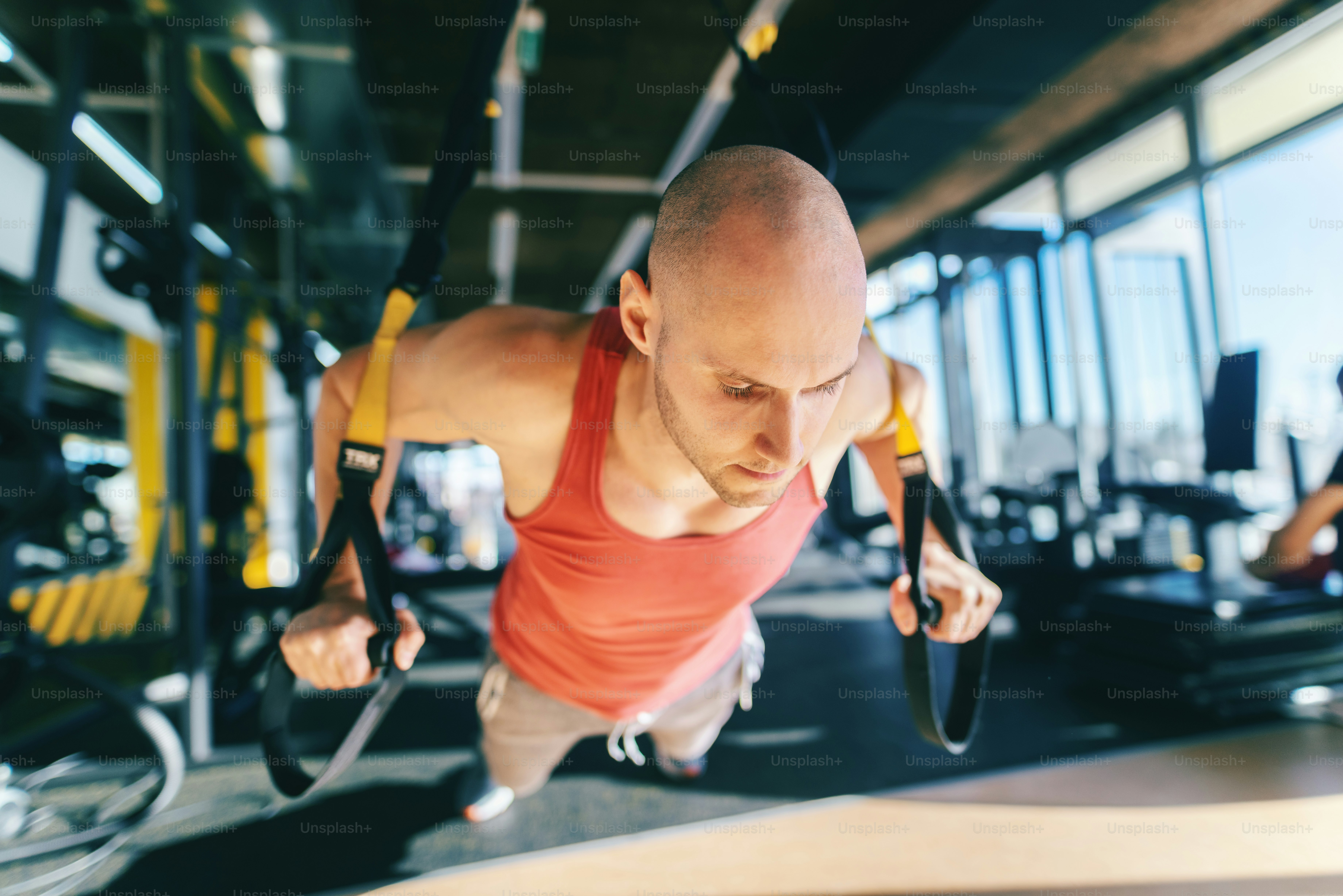Close up of bald Caucasian man in sportswear doing push ups with trx rope  with serious facial expression. Gym interior. photo – Man Image on Unsplash