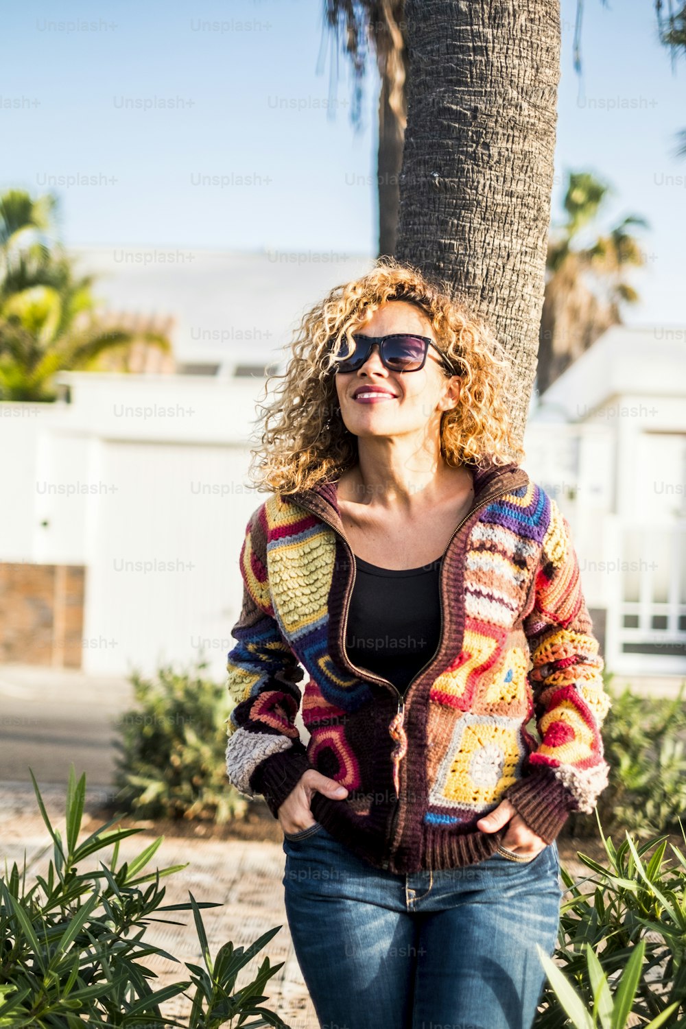 Vertical portrait beautiful curly middle age woman enjoying the sun and the leisure outdoor day activity smiling and resting - trendy fashion clothes and sweater for model casual concept image of happy people