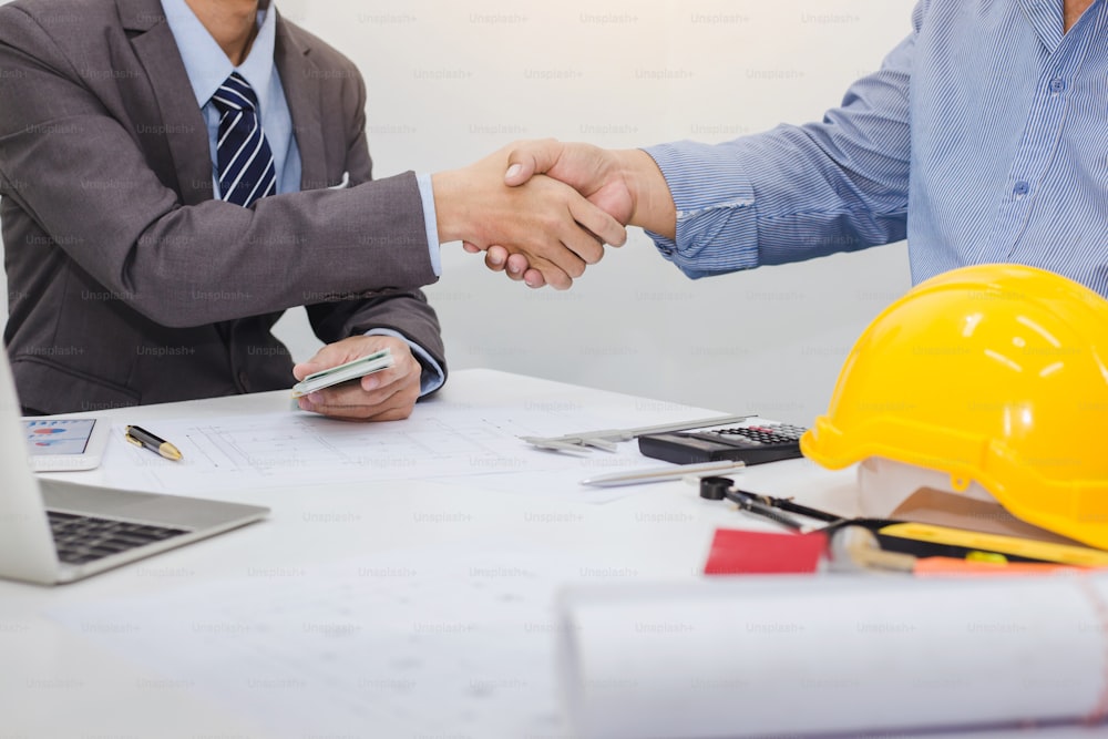 Architects and businessman shaking hands to start the project together at the meeting.