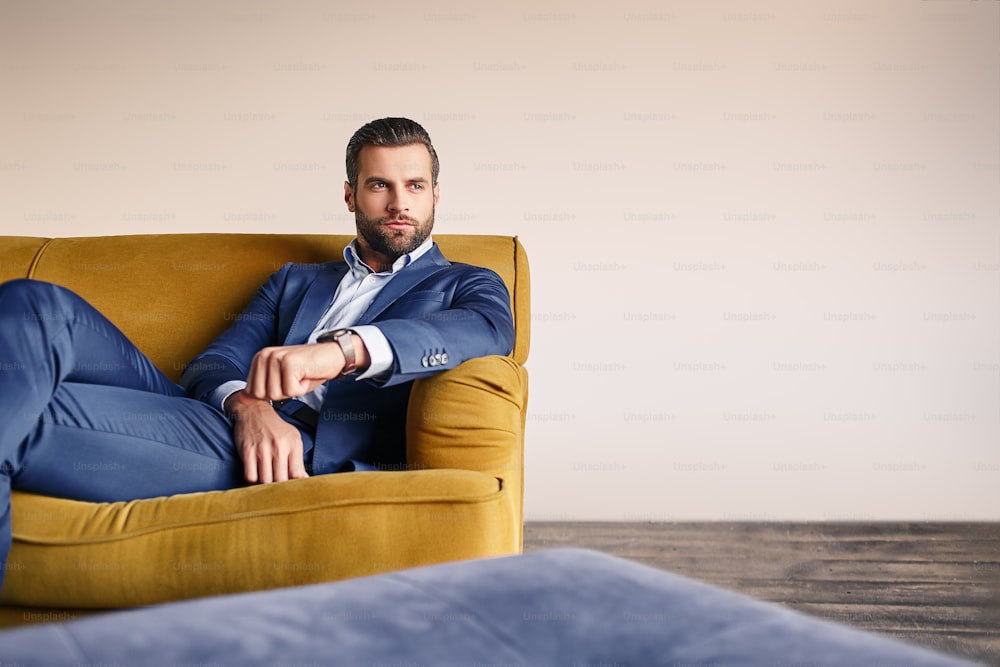 Se sentir détendu... Un homme d’affaires beau et bien habillé se repose sur un canapé et pense aux affaires. Look de mode. Concept d�’entreprise.