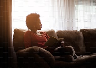 Book is her peace. African American woman reading book at home.