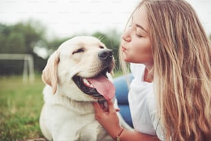 Marco con una hermosa muchacha con un hermoso perro en un parque sobre hierba verde