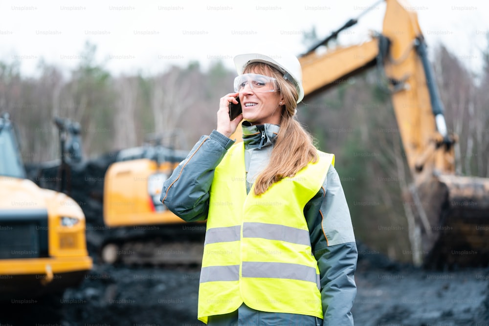 Donna operaia in miniera a cielo aperto che utilizza il telefono che parla con il manager
