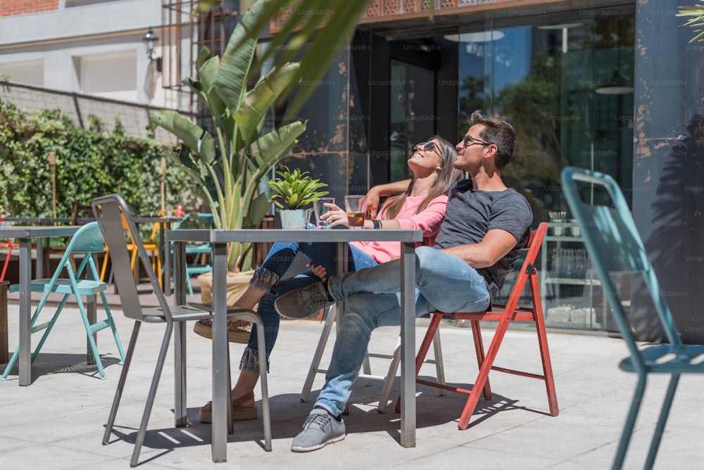 Glückliches junges Paar sitzt entspannt auf einer Restaurantterrasse