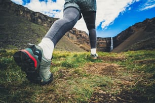 Woman traveler trekking in Icelandic summer landscape at the Hengifoss waterfall in Iceland. The waterfall is situated in the eastern part of Iceland.