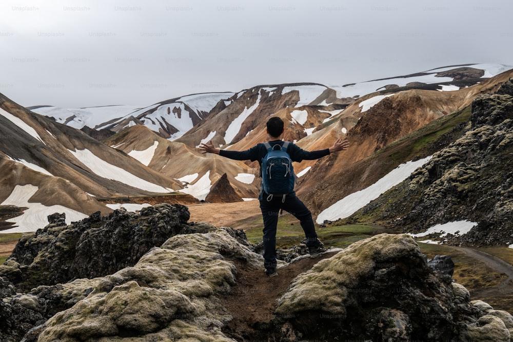 Traveler hiking at Landmannalaugar surreal nature landscape in highland of Iceland, Nordic, Europe. Beautiful colorful snow mountain terrain famous for summer trekking adventure and outdoor walking.