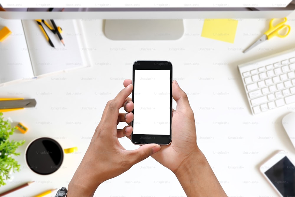 Oman hands holding smart phone with blank copy space screen on office desk.