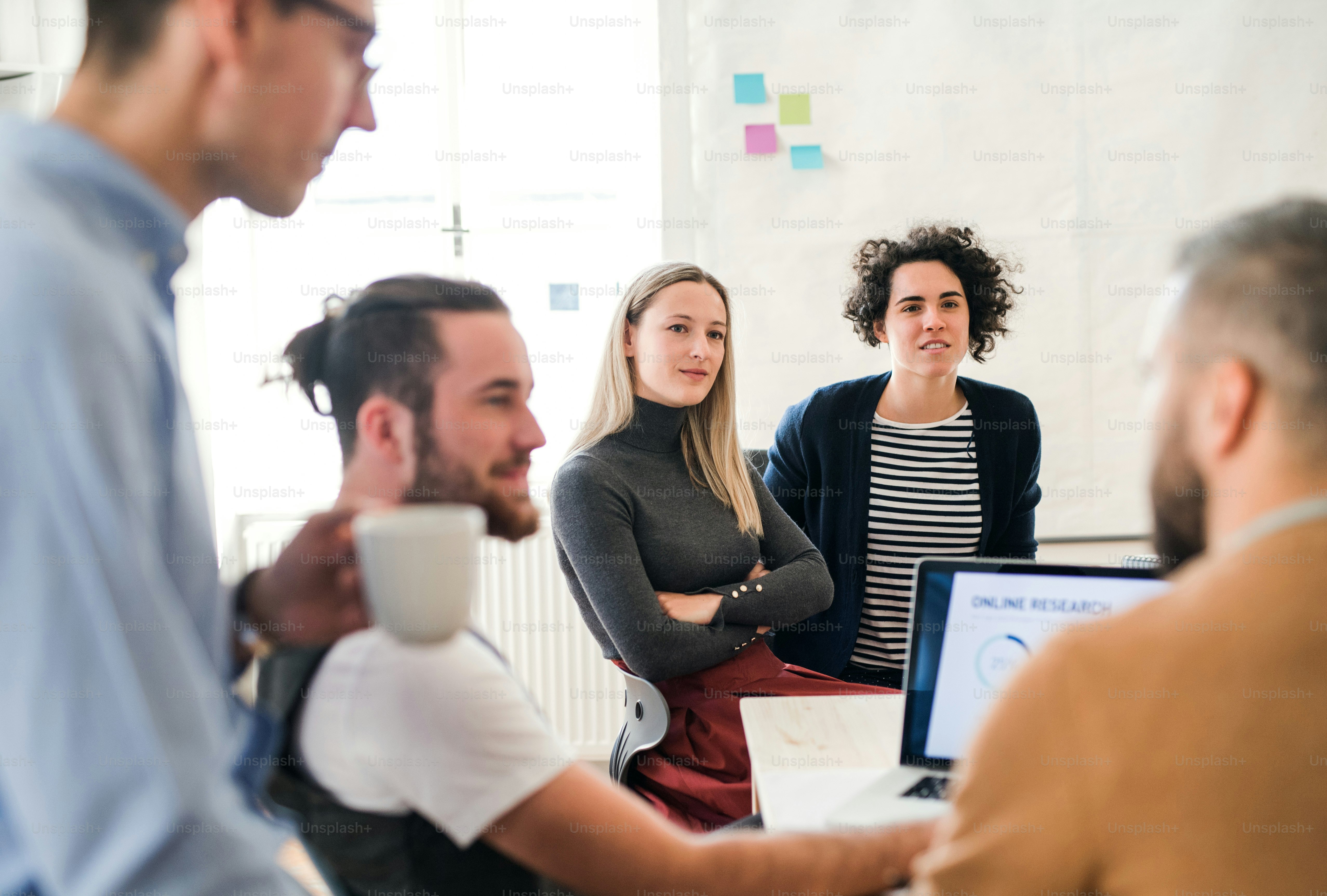 Group of young, cheerful, male and female businesspeople with laptop working together in a modern office