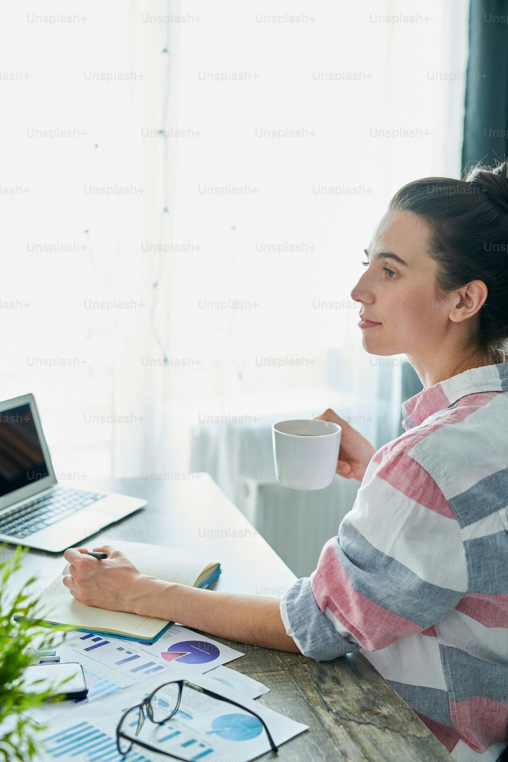 Side view portrait of pensive young woman enjoying coffee while working at home, copy space