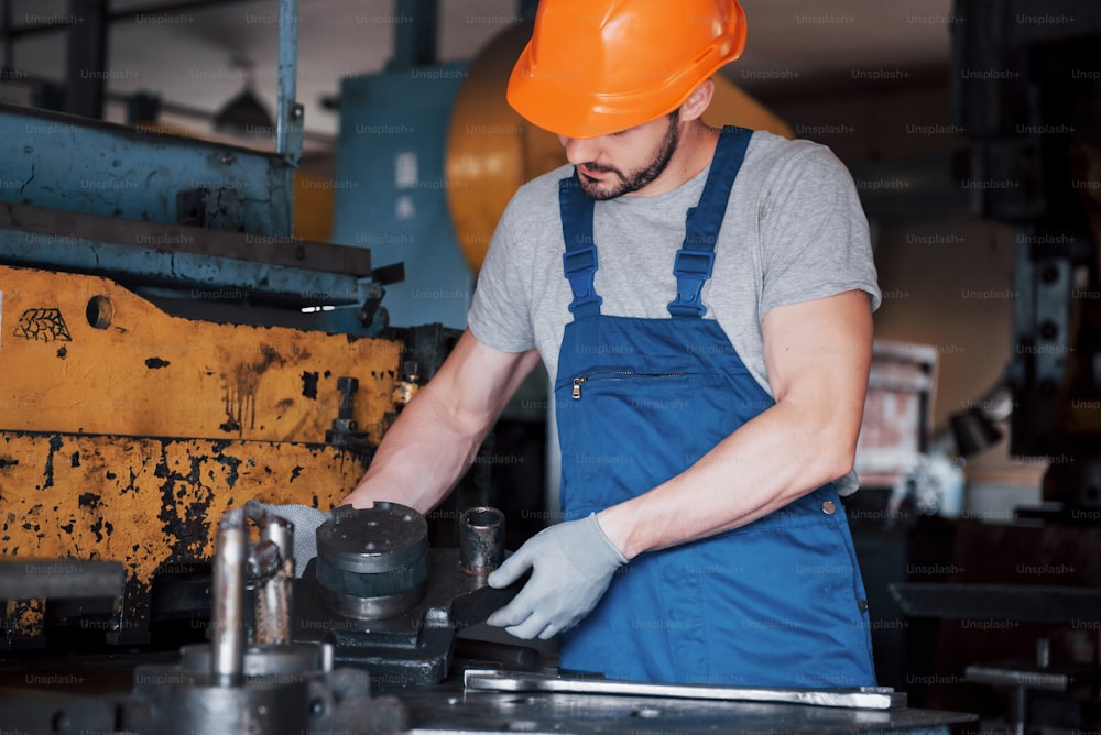 Portrait of a young worker in a hard hat at a large waste recycling factory. The engineer monitors the work of machines and other equipment.