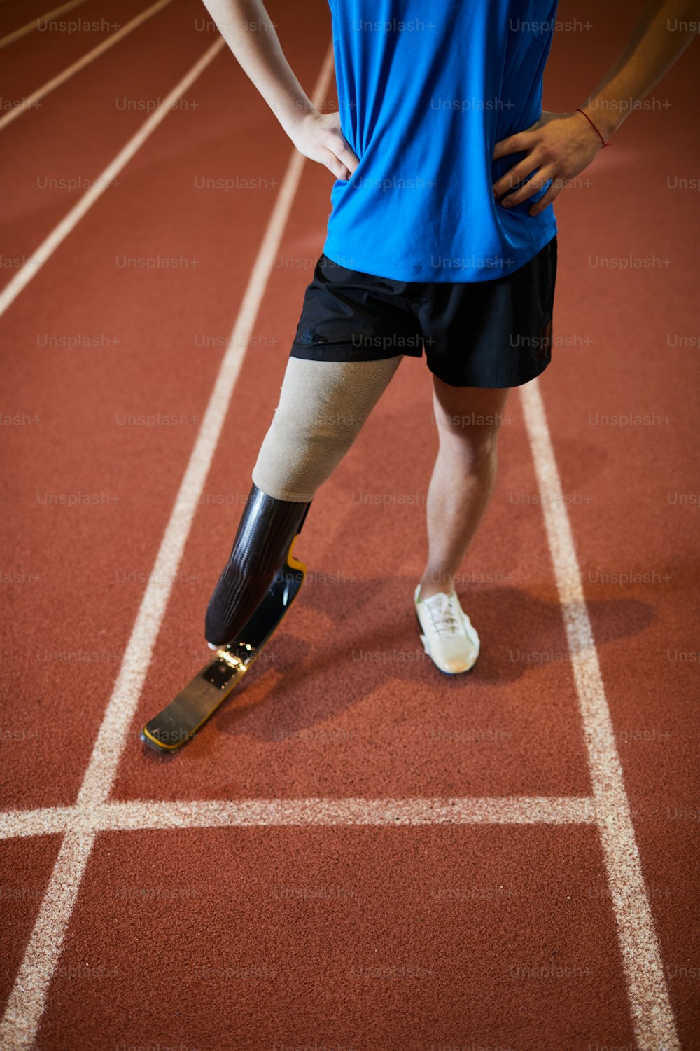 Sección baja de deportista paralímpico de pie en la pista de carreras junto a la línea de salida antes de la competencia o el maratón