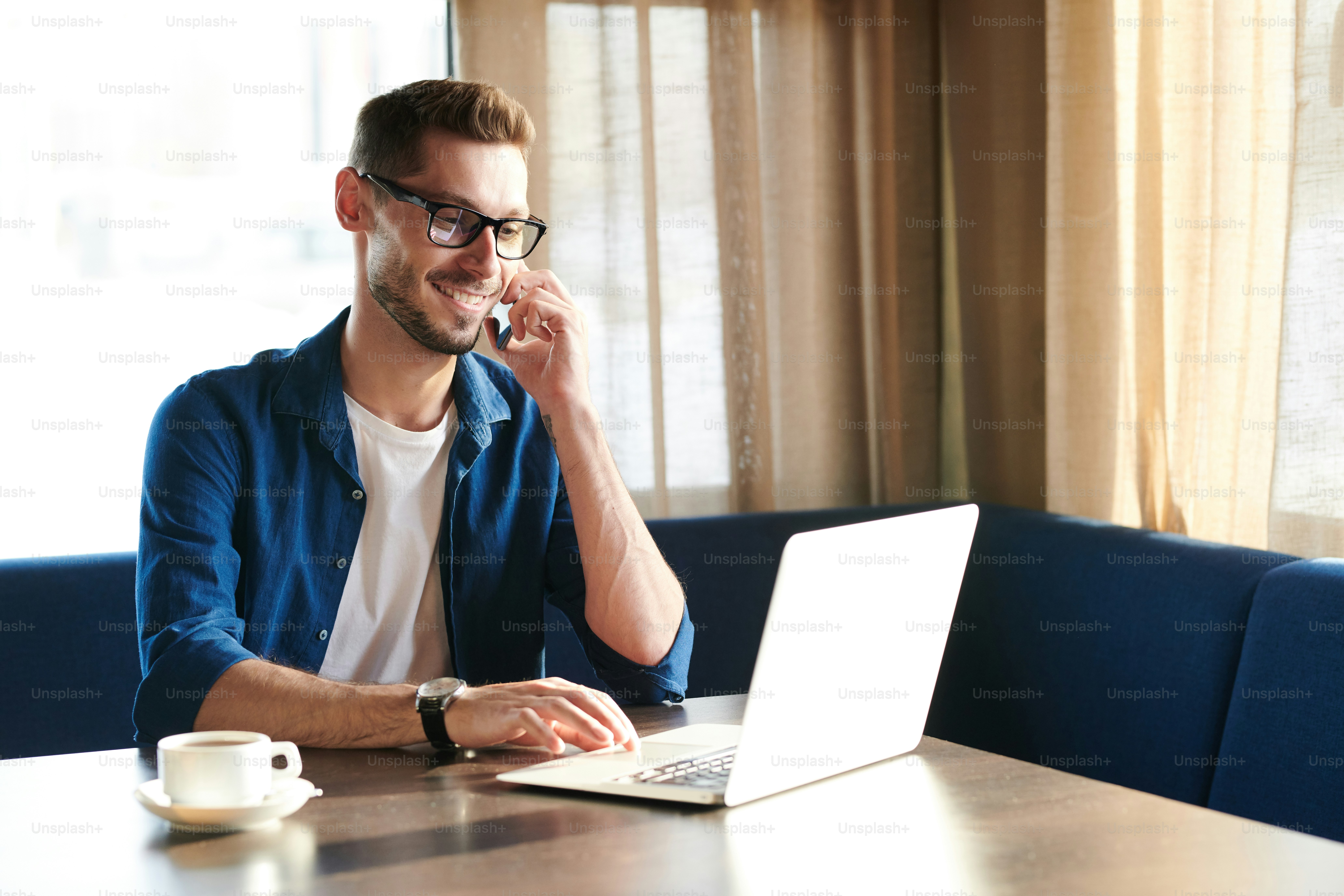 Young busy home office manager talking by smartphone while looking at