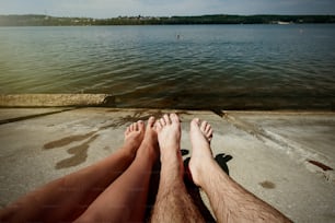 happy stylish couple legs, sunbathing at the beach, summer vacation, space for text